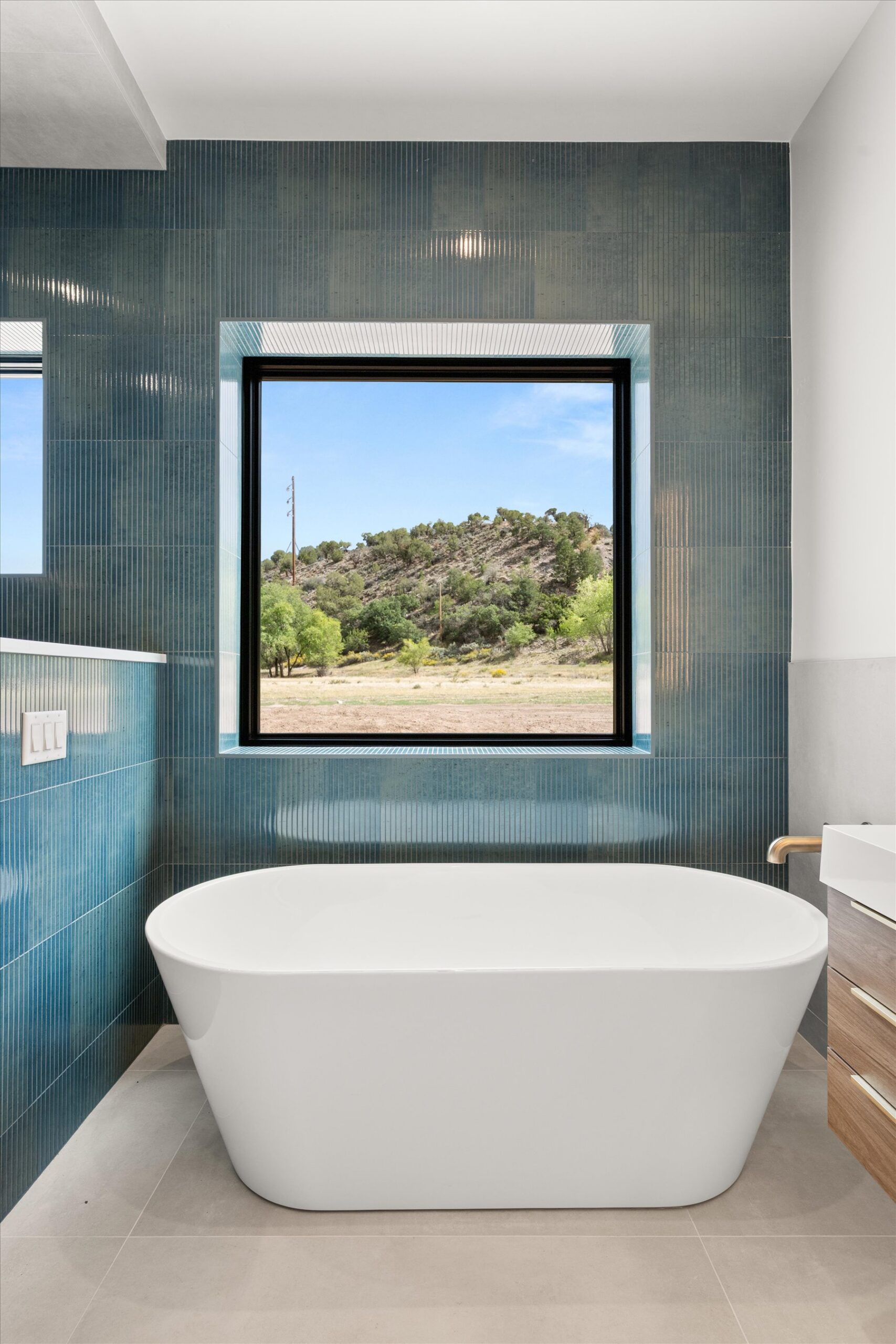 Soaking tub beneath window with tile surround